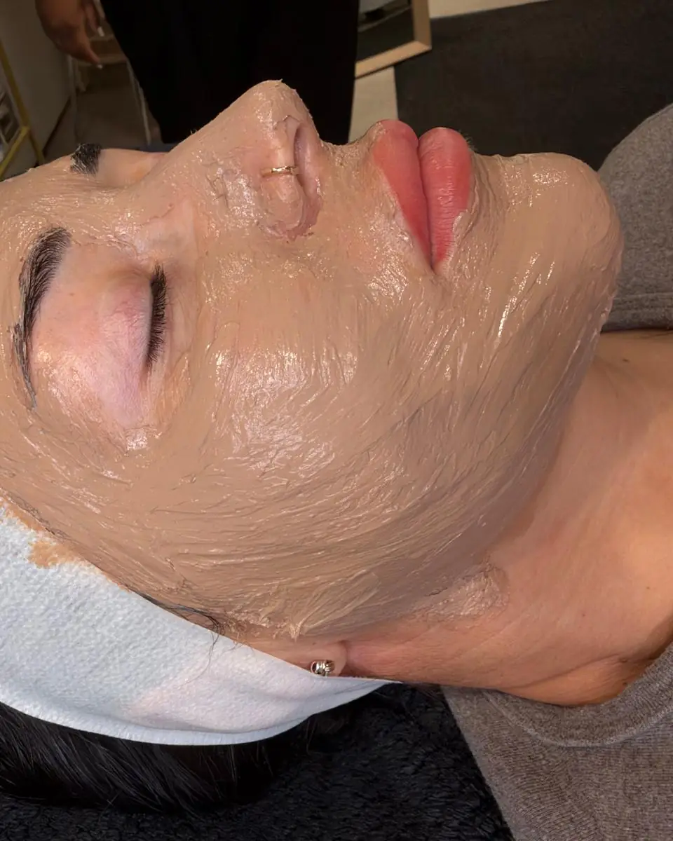 A client lying back in the Glow By Yaz treatment room wearing the Cosmelan mask during treatment, hair held back with a white headband