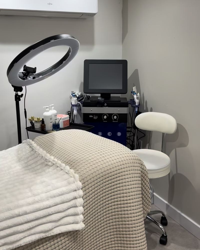 The treatment room at Glow By Yaz, Bletchley, with a made-up treatment couch, a ring light and facial equipment